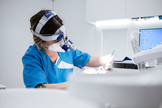 Higienista dental realizando tratamiento de limpieza dental en Santander